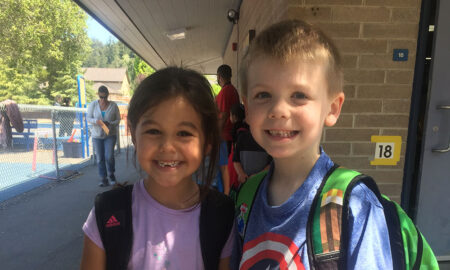 two kids smiling outside a school